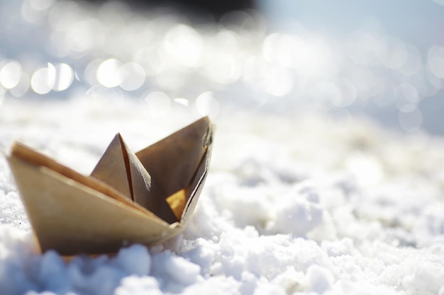 Paper boat in the water on the street. The concept of early spring. Melting snow and an origami boat on water waves.