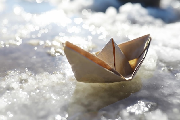 Paper boat in the water on the street. The concept of early spring. Melting snow and an origami boat on water waves.