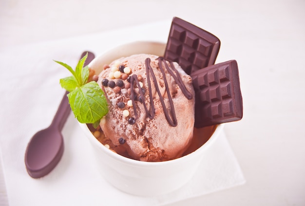Paper bowl of chocolate ice cream with mint leaf 