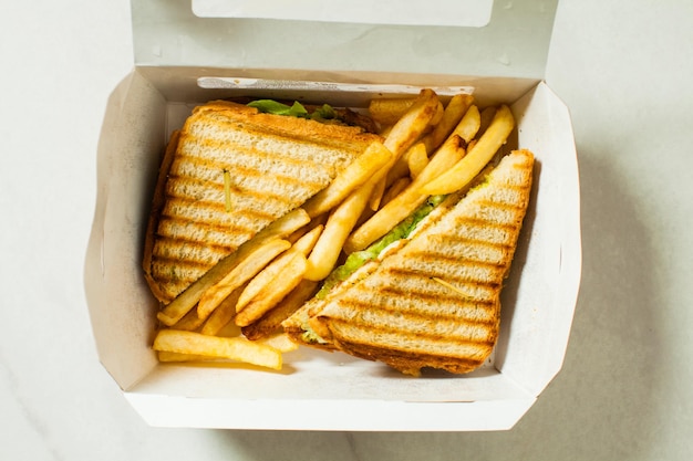 Scatola di carta con sandwich di pollo con patatine fritte, vista dall'alto