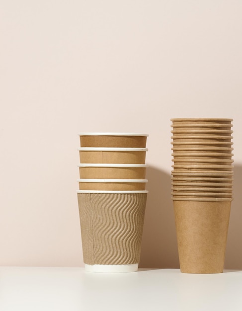 Paper cardboard brown cups for coffee and tea, beige background. Eco-friendly tableware, zero waste