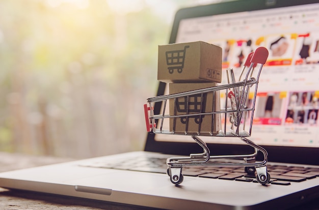 Paper cartons with a shopping cart logo and credit card on a laptop keyboard