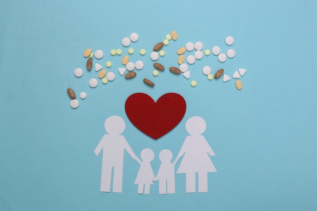 Paper chain family, pills and red heart on blue, health insurance concept