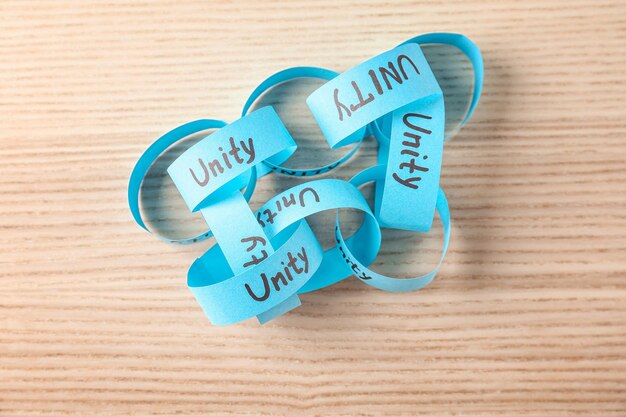 Photo paper chain with word unity on wooden background