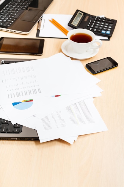 Paper charts and modern office tools on table