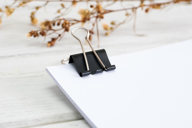 Paper clip and white paper on white wood table