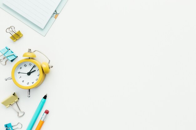 Paper clips, mechanical clock, pen, pencil and notepad on white background. Work and education concept.