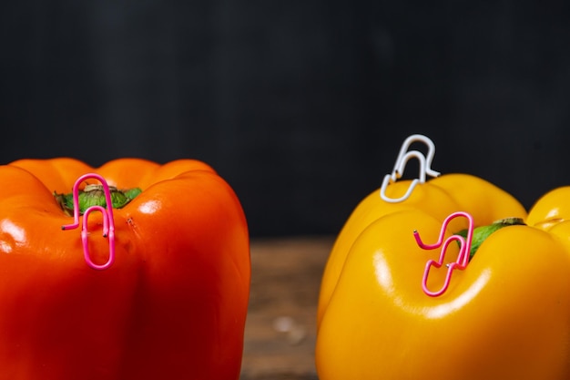 Paper clips white and pink sitting on a yellow bell pepper and talking or having a conversation