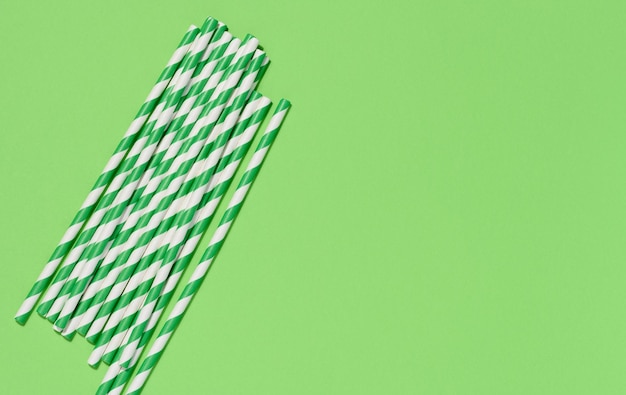 Photo paper cocktail straws on a green background top view