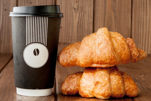 Foto carta tazza da caffè e croissant su sfondo di legno, copia dello spazio.