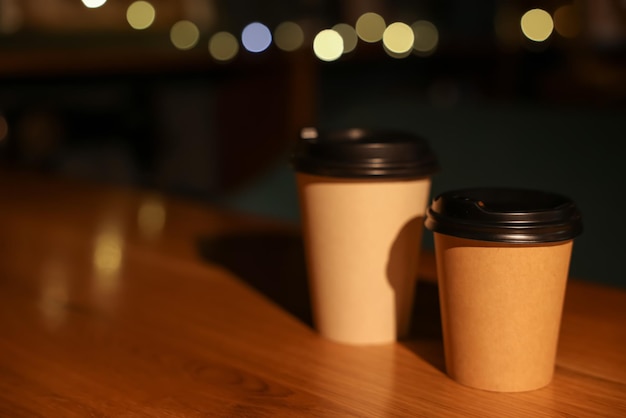 Paper coffee cups on wooden table in cafe Space for text