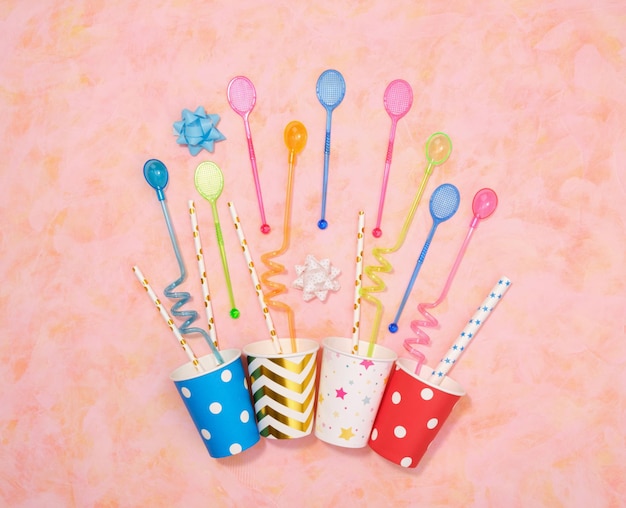 Paper colored cups for alcoholic delicious cocktails straws and sticks in the form of rackets Flat lay birthday composition