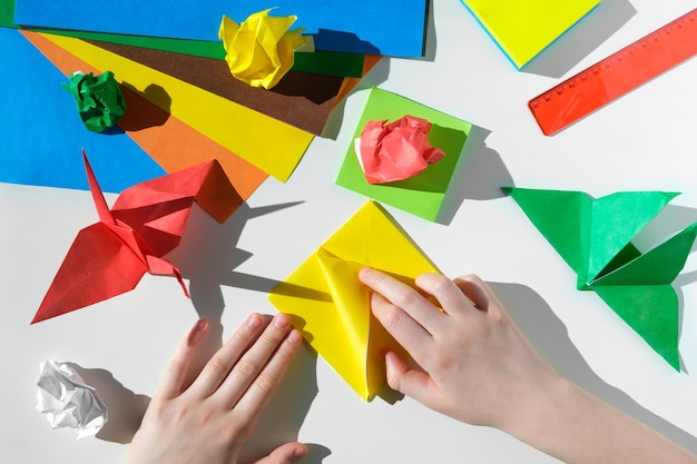 Paper crafts scissors colored paper on white table Origami Children working place Preschooler