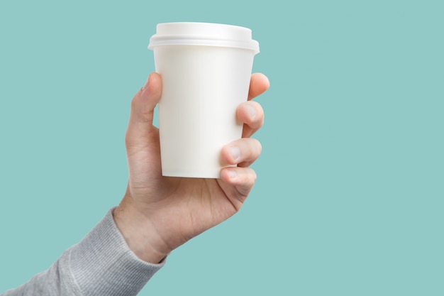 A paper cup of coffee in the hand. White paper cup of coffee in hand isolated