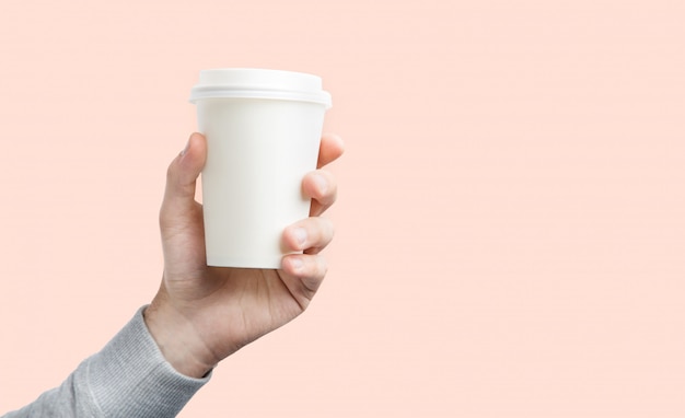 A paper cup of coffee in the hand. White paper cup of coffee in hand isolated