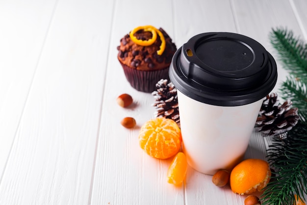 Paper cup of coffee surrounded by Christmas decorations