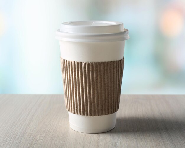 Paper cup of coffee on table on bright background