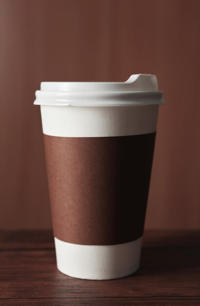 Paper cup of coffee on table on wooden background