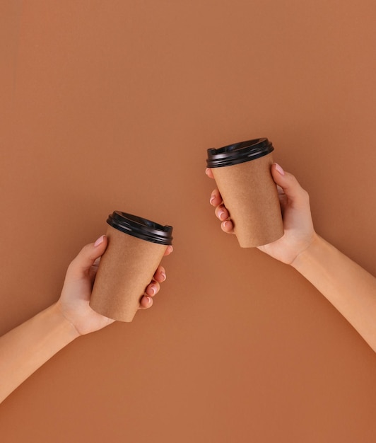 Paper cup of coffee with place for logo in hand on beige background