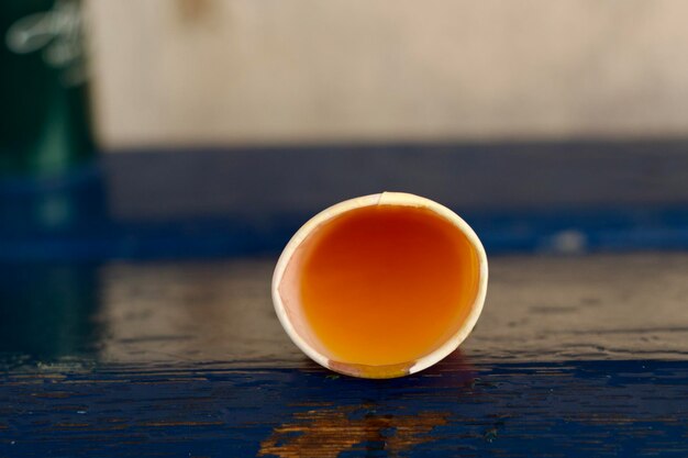 A paper cup on its side and spilling out an orange coloured beverage