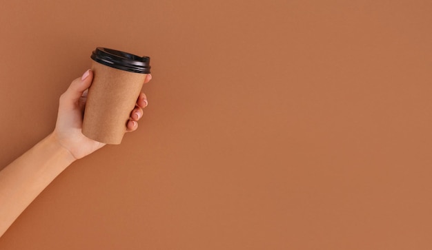 Фото Бумажная чашка кофе с местом для логотипа в руке на бежевом фоне