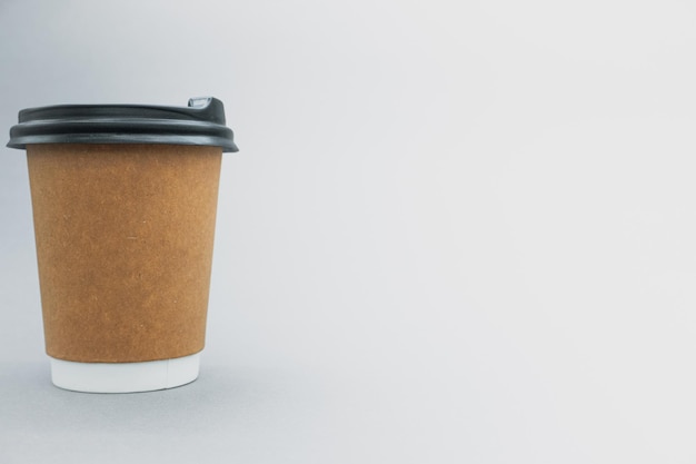 Paper cup for tea and coffee, on the left side, on a gray background. There is space for text.