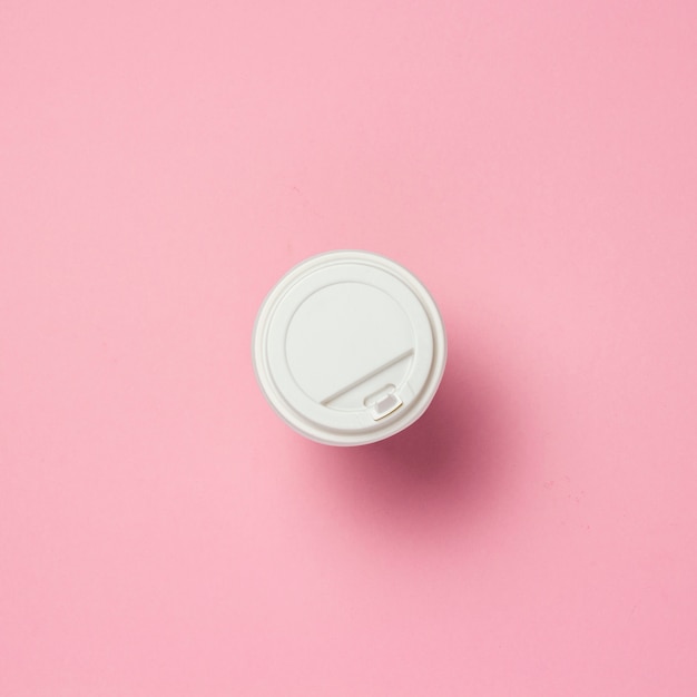 Фото Бумажный стаканчик с пластиковой крышкой, кофе или чай, на розовом фоне. концепция быстрого питания, пекарня, завтрак, сладости, кафе, еда на вынос. копировать пространство. плоская планировка, вид сверху.
