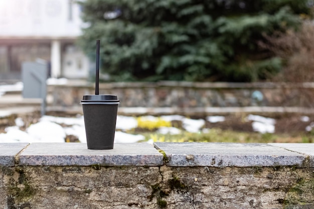 Бумажный стаканчик с кофе на бетонной скамейке