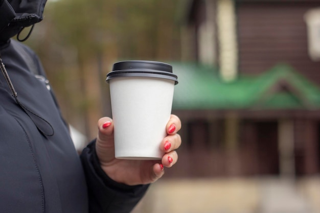 A paper cup with coffee in the hand of a young woman