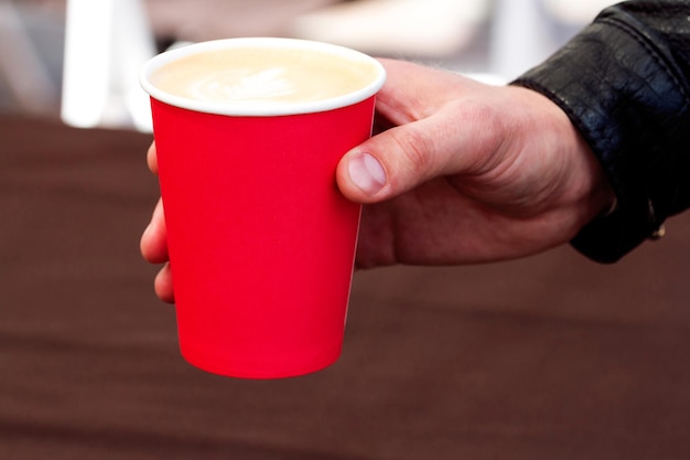 Paper cup with coffee in hand