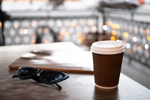 Foto tazza di carta con caffè e una rivista su un tavolo