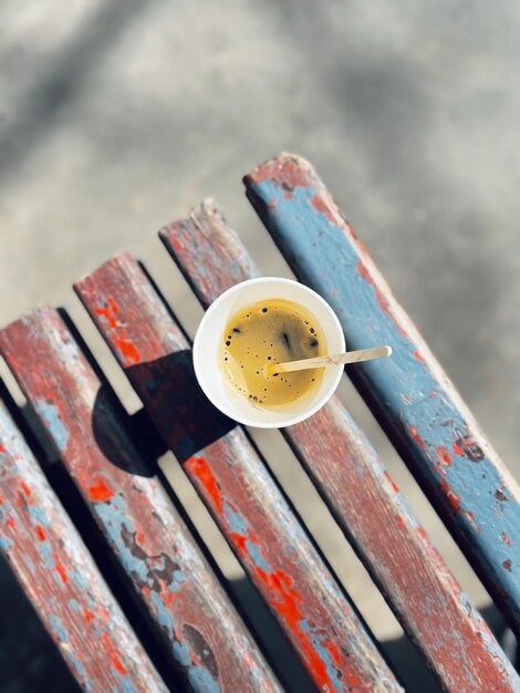 Foto coppa di carta con il caffè su una vecchia panchina in un soleggiato giorno d'estate