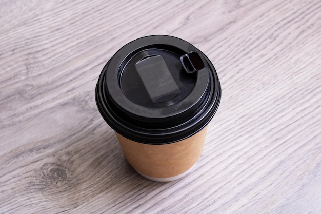 Paper cup with coffee on wooden background