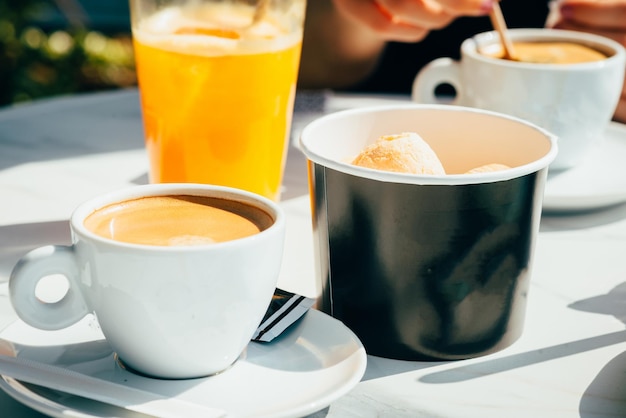 Paper cup with ice cream balls near the cup of coffee and a glass of juice