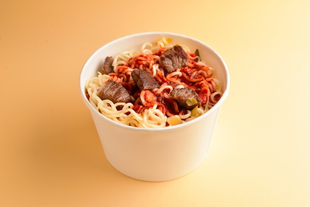 Paper cup with instant ramen noodles with beef and vegetables.