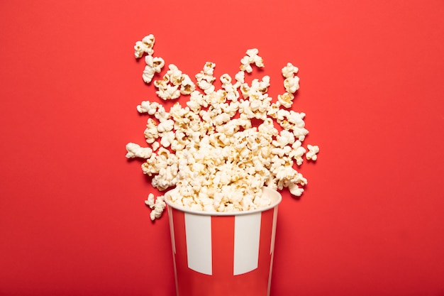 Paper cup with popcorn on a red background