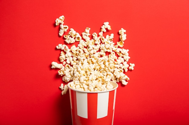 Paper cup with popcorn on a red background