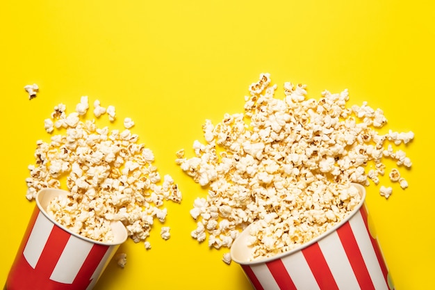 Paper cup with popcorn on a yellow background, place for text.