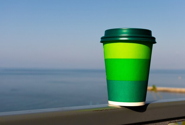 Paper cup with tea coffee drink on a glass table belong to the background plant and a green wall. Zero West Concept.