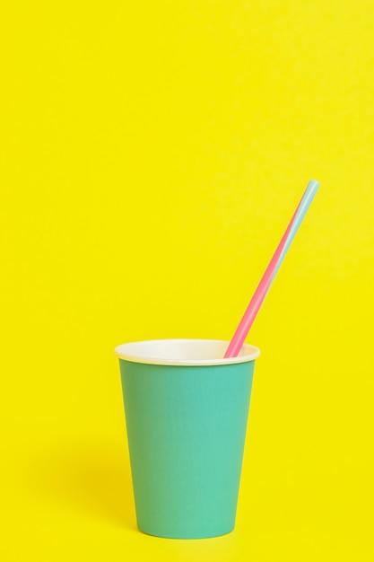 Paper cup with tube on yellow background. Text space