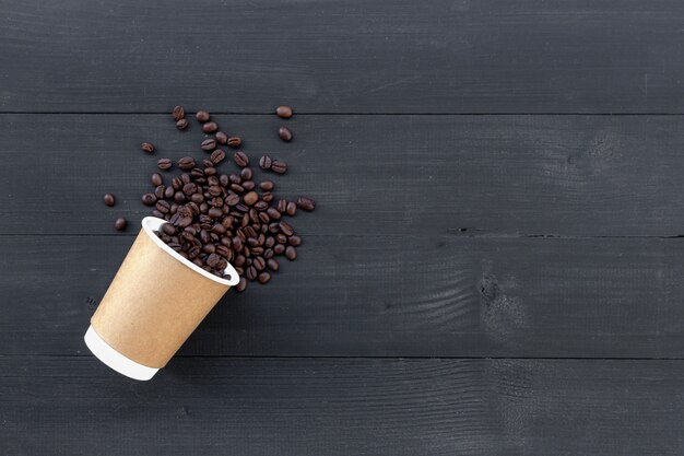 Paper cups of coffee and bean on black wooden background. top view