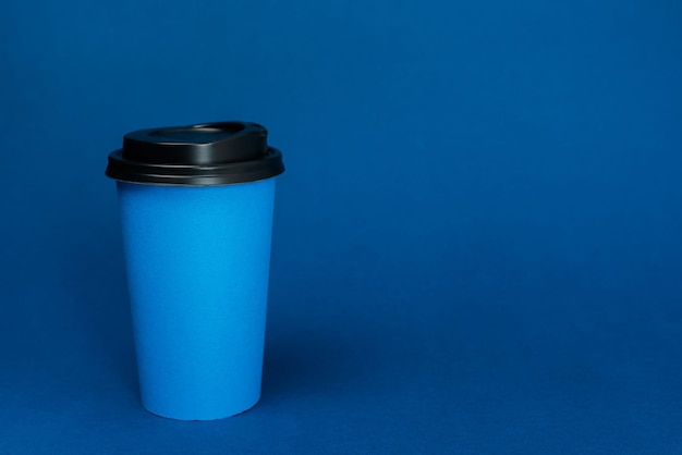 Photo paper cups with coffee on classic blue background with copy space