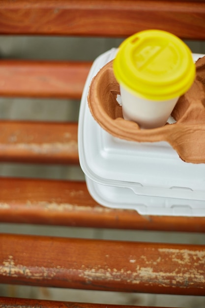 Photo paper cups with coffee and fast food boxes to go on a park bench outdoor takeaway food concept