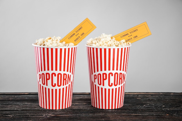 Photo paper cups with tasty popcorn and tickets on wooden table