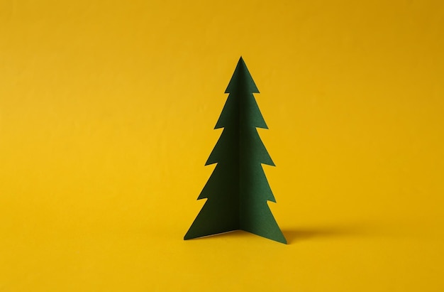 Paper cut Christmas tree on yellow background