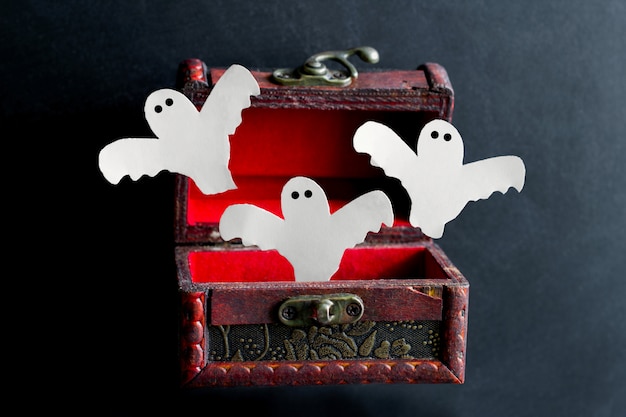 Paper cut scary ghosts fly out of an old vintage  wooden chest 