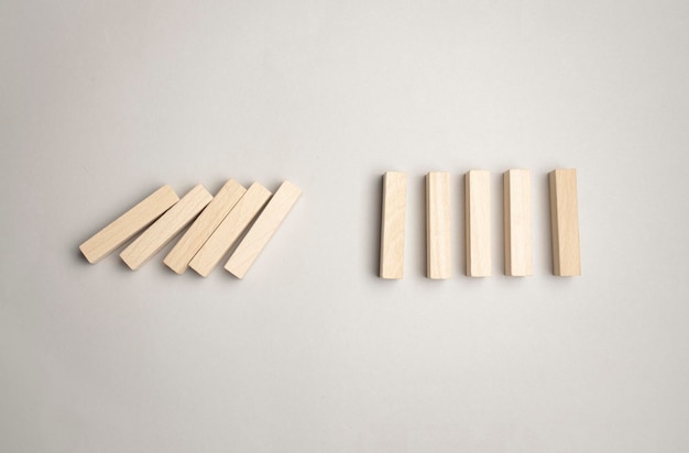 Photo paper cut silhouette of a man stopping falling dominos in a conceptual image. over gray background.