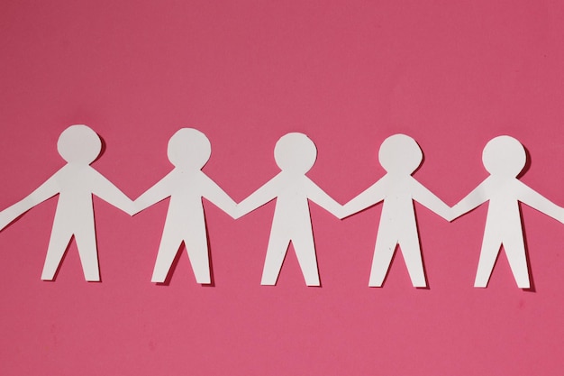 Paper cut Style concept of a leader and relationship with friendship and hand-holding of people in symbolic form on Inspiration style and modern pink paste background - 3D rendering