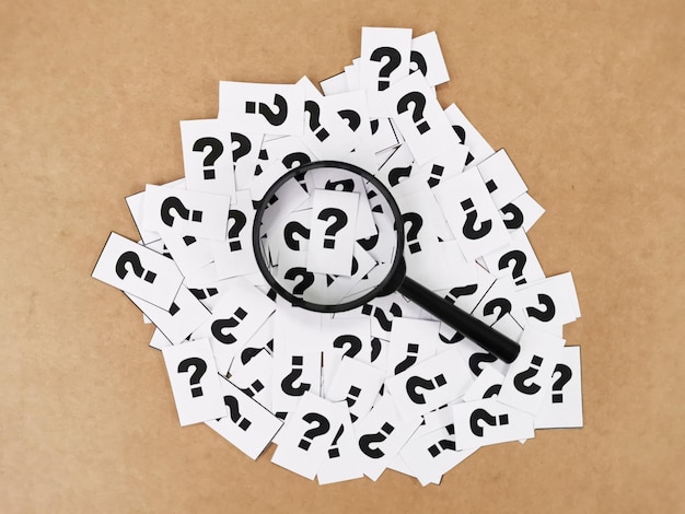 paper cut with question mark symbols and magnifying glass