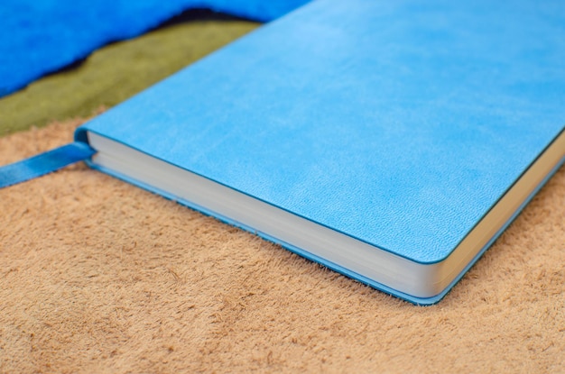 책갈피가 있는 파란색 가죽 커버의 종이 다이어리. 여러 색상의 가죽 조각에.